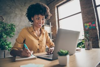 A woman smiling while sitting at a table and using a laptop