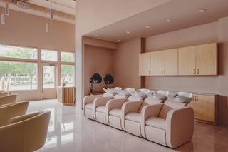 Entrance door and windows with view of trees, chairs and wash basins at the Pressed Roots hair salon in Texas