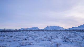 northern lights abisko with a large mountain in the shape of a U valley in the background.