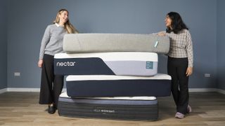 Tom's Guide's sleep editor and mattress tester stand either side of a tall pile of mattresses that we have tested and recommend as the best choices for all sleepers, including the Nectar Classic mattress, the Helix Midnight Luxe and the Siena Mattress