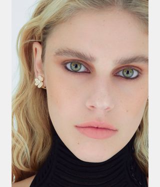 woman with blonde hair and green eyes wearing gold jewellery