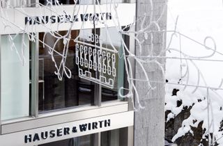 An upclose section of the building featuring te grey brick wall, clear glass windows and the name HAUSER & WIRTH written on the building