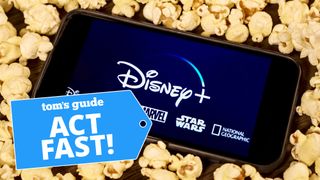 Smartphone lying on bed of popcorn while showing Disney Plus logo