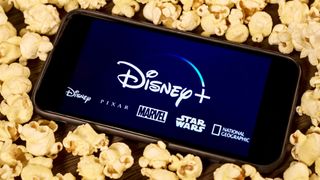 Disney Plus logo on a smartphone surrounded by popcorn