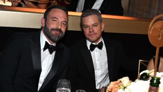 Matt Damon and Ben Affleck smilng at a table during the Golden Globes