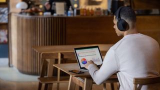 Man using Sony WH-1000XM5 with his laptop in a coffee shop