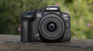 The Canon EOS R10 camers sitting on a wooden bannister