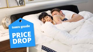 A couple lie asleep on the WinkBed mattress, with a Tom&#039;s Guide price drop deals graphic (left)