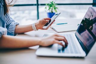 Woman using smartphone and laptop