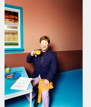 elton john with eggs on his face, drinking tea