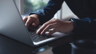 A close up photo of someone&#039;s hands while typing on a laptop