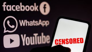 In this photo illustration the word censored is seen displayed on a smartphone with the logos of social networks Facebook, WhatsApp and YouTube in the background.