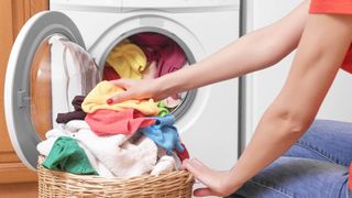 Person kneeling and loading a washing machine