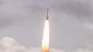 a large white rocket flies through the sky above a cone of flame