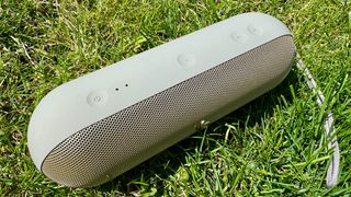 Beats Pill Bluetooth speaker on grass showing control panel