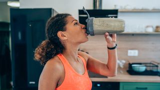 a photo of a woman drinking from one of the best protein shakers 