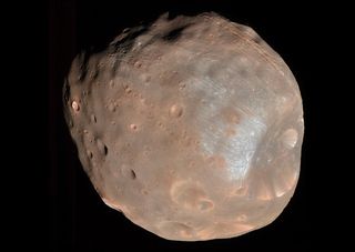 Cratered moon Phobos has a particularly large crater on the right side of the image and is brown/gray in color.