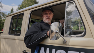 Bearded comedian Greg Davies looks grumpily out of the window of a vintage beige work truck as Paul 'Wicky' Wickstead in season 3 of "The Cleaner"