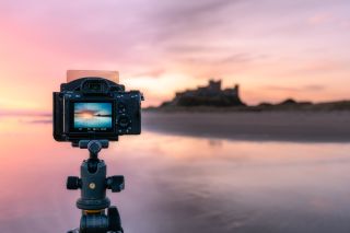 A camera on a tripod pointed towards a misty landscape