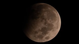 a close up view of the moon during a partial lunar eclipse with a portion of the moon obscured by a dark shadow. 