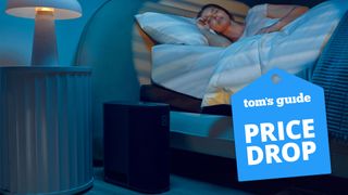 A woman lies in her bed at night, sleeping well. On the floor next to her is the Eight Sleep smart mattress cover Pod. A Tom's Guide Eight Sleep price drop deals graphic (left)