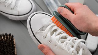 A pair of white canvas shoes being cleaned