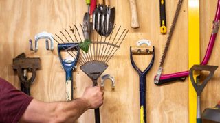 assortment of garden tools stored on wall hooks