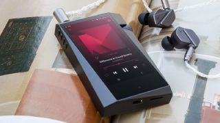 Astell & Kern music player on a magazine next to earbuds