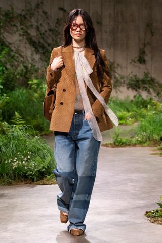 Model on the runway wearing pussybow shirt and jeans at the Gucci Cruise 2025 runway show