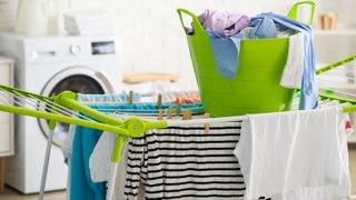 Clothes hung on a clothes rack dryer with a basket of clothes on top