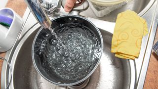 A pot being filled with water in a sink