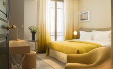 Hotel bedroom with green ombre curtains, wooden furniture and white and green bedding