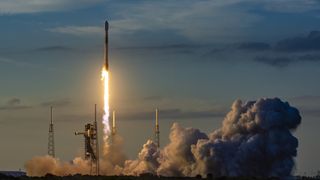 A white and black SpaceX rocket launches into the twilight sky.