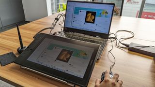 Huion Kamvas Pro 13 2.5K graphics / drawing tablet being used on a wooden table in an office space in the daytime.