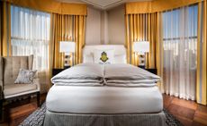 Hotel room with yellow curtains and white coloured bed