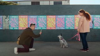 A man kneels to scan a woman&#039;s dog with the iPhone 16 