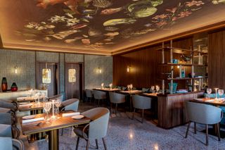 Vero restaurant, with food-themed ceiling fresco, blue armchairs and tables laid with Murano glasses