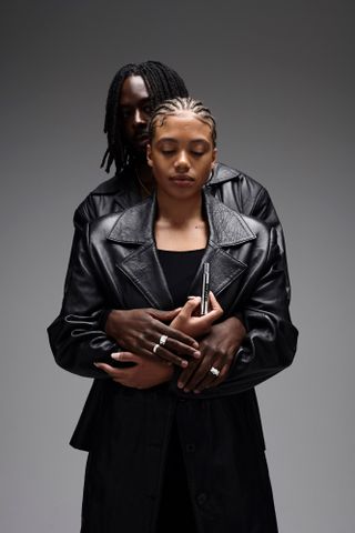 woman and man in black leather coats holding uniform fragrance