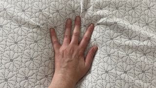 A hand pressing into the surface of the Zinus Green Tea Memory Foam Mattress