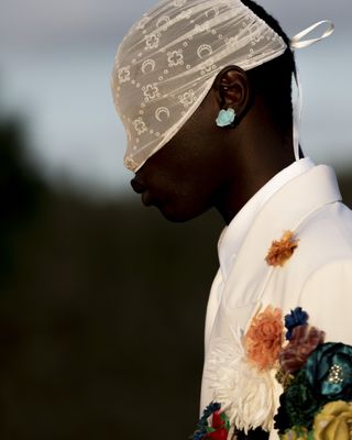 Man on Marine Serre runway show wearing veil and flowers