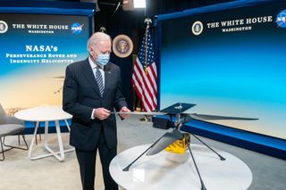 President Joe Biden examines a model of NASA's Mars helicopter Ingenuity, which on April 19 became the first aircraft to perform a powered, controlled flight on a world beyond Earth.