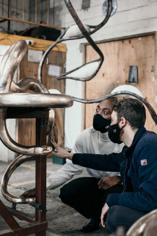 Rich Mnisi with artist Trevor Potter looking at a work in progress of a console in the workshop