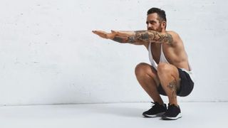 Man in a low squat with arms extended at shoulder height during gorilla walk exercise