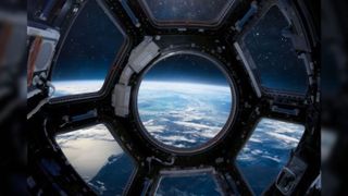 Looking through the Cupola porthole to see Earth below. 