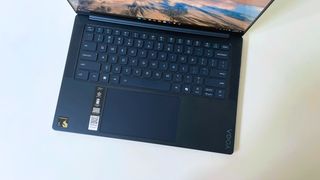 The keyboard deck of the Lenovo Yoga Slim 7x seen from above on a white desk