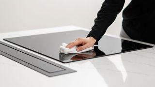 Woman cleaning an ceramic induction cooktop