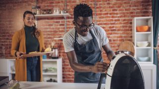 Young man and woman preparing fries using air fryer