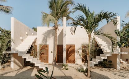 A white building by the beach with a staircase by each side