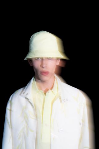 Man wearing Véronique Nichanian Hermès menswear and hat against black background