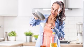 Woman pouring oil into bottle using a funnel